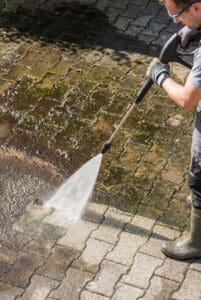 A man powerwashing a patio.